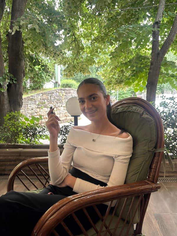 Woman sits outdoors with phone and drinks in public square