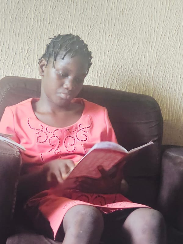 Young person reading book in chair, Nkwelle Nigeria