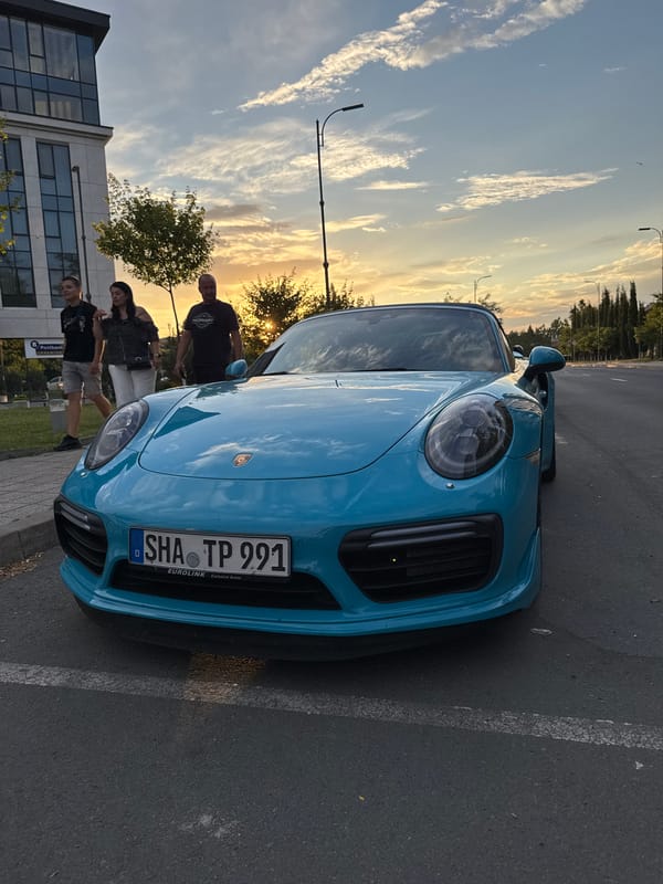 Blue Porsche draws attention on a Burgas street at sunset