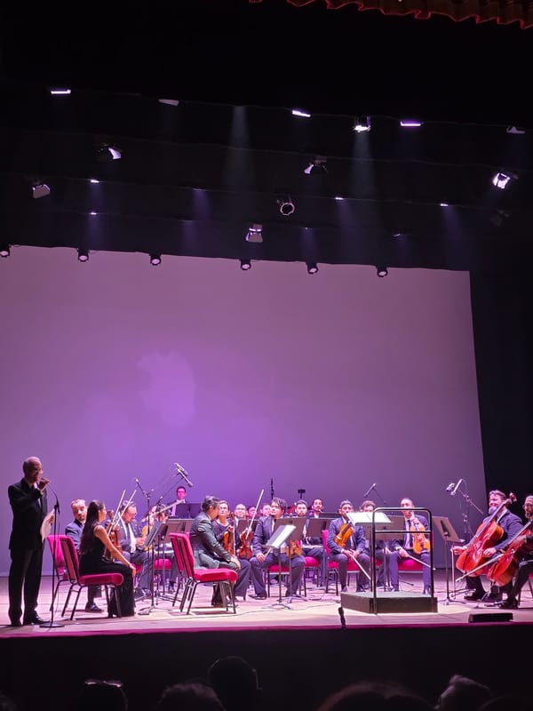 Orchestral performance underway on a purple-lit stage in Iquique