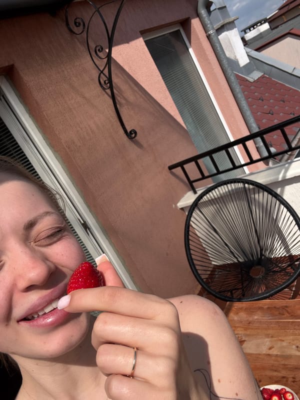 Person enjoys fresh strawberries on Sofia balcony overlooking city