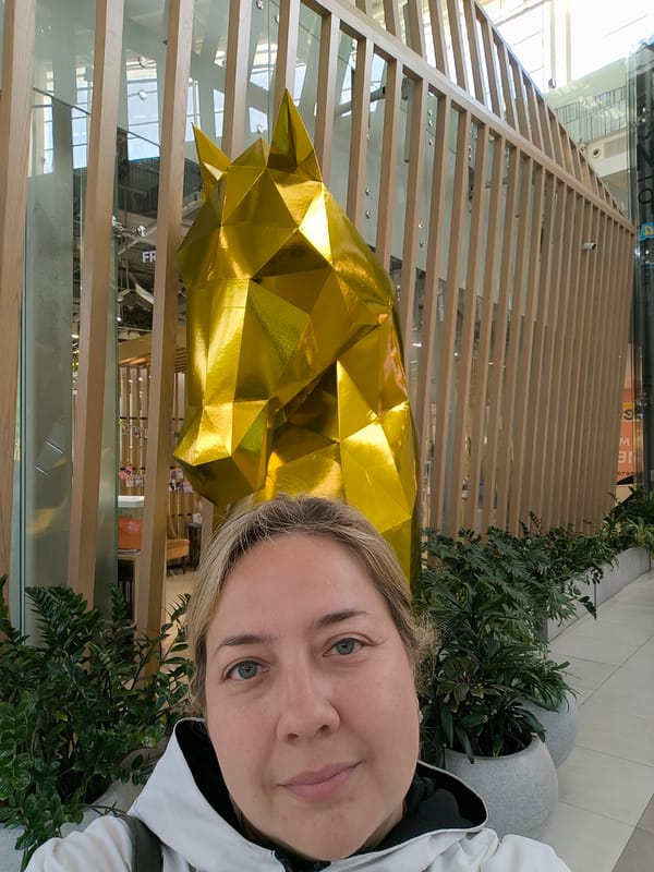 Selfies and sightseeing around a golden horse sculpture in a modern mall
