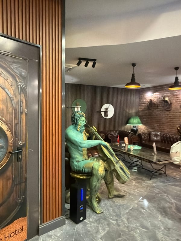 Ornate hotel lobby features large verdigris statue centerpiece