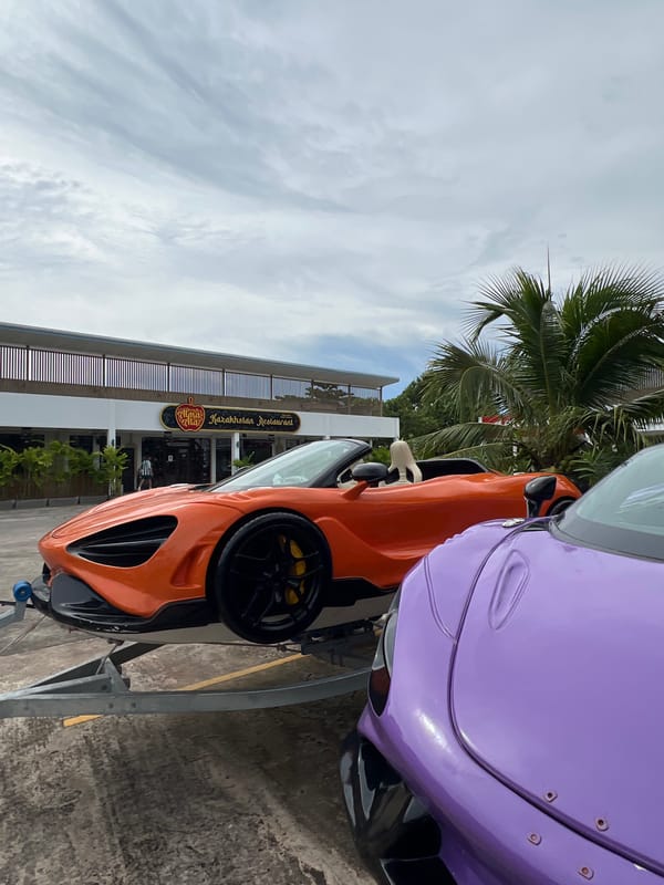Two McLarens parked on trailers outside a Chalong restaurant