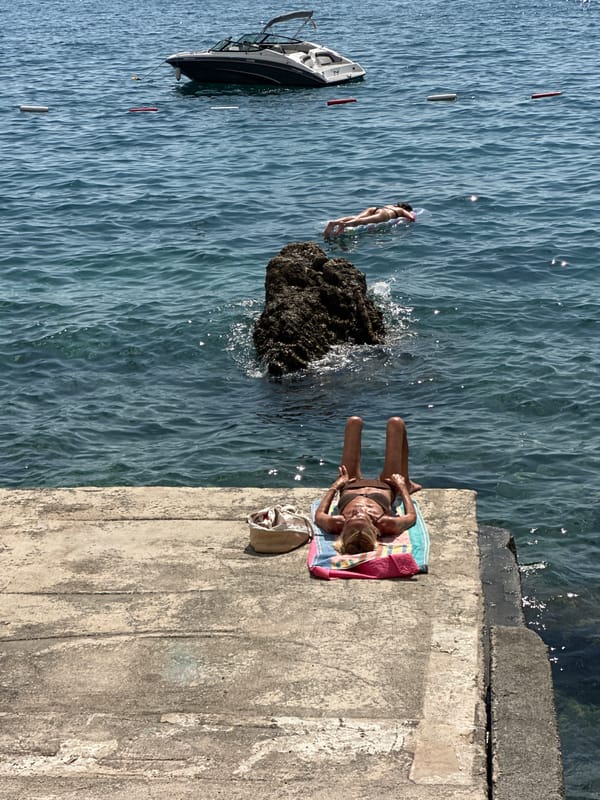 Budva beach in full summer swing — parasails, boats, and crowds
