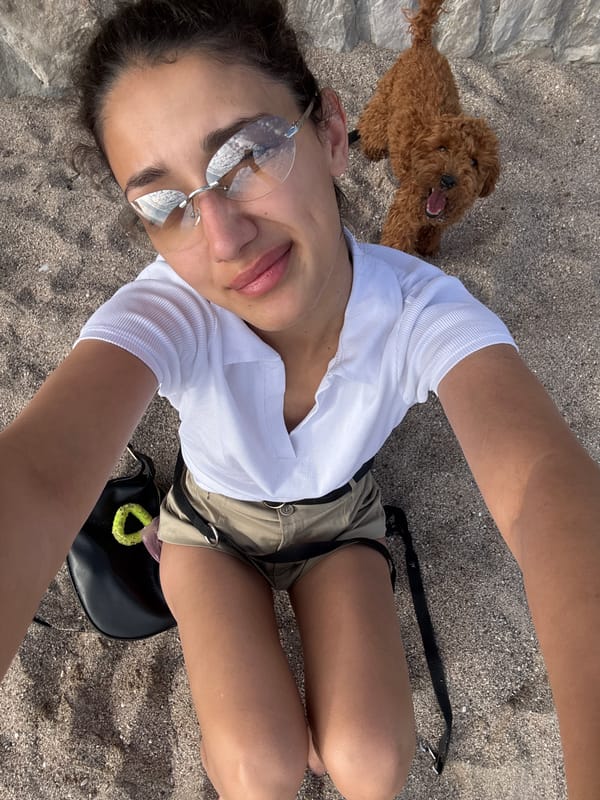 Woman takes selfie, dog plays at Montenegro beach