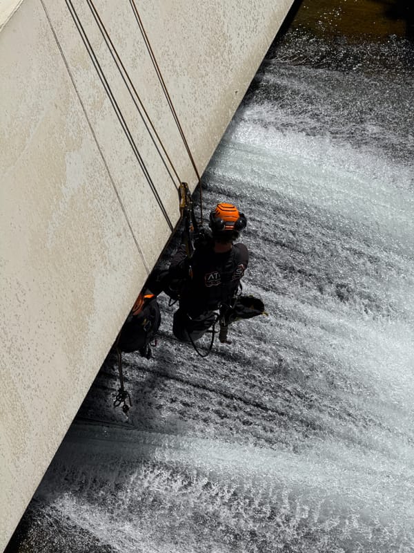 Two rappellers descend concrete dam face in Curbans, France