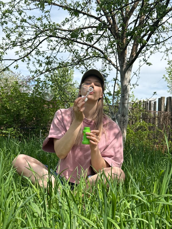 Woman blows bubbles in grass in Chaikovsky, Russia