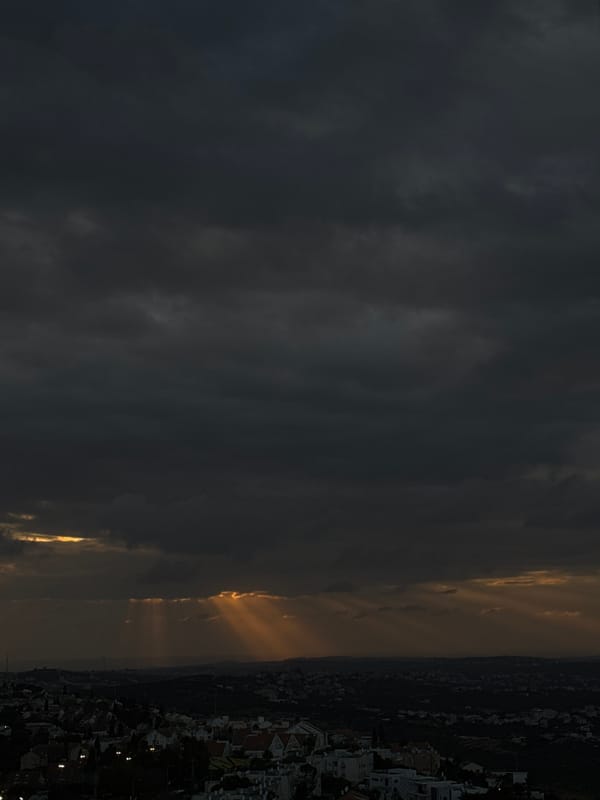 Sunlight breaks through dark clouds over urban landscape
