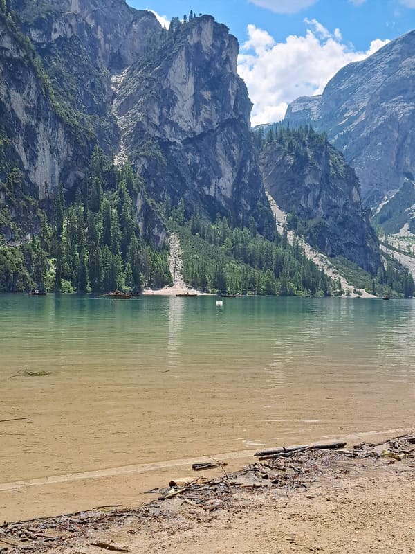 Alpine lake day: clear water, rowboats, stone lodges, mountain backdrop
