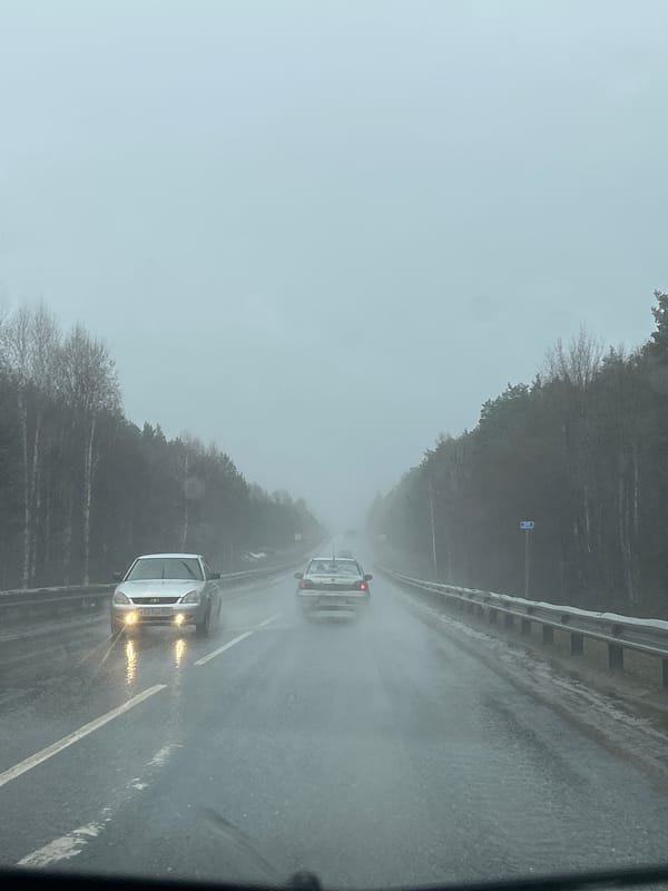 Vehicles travel wet highway during rainy day in Chaykovsky