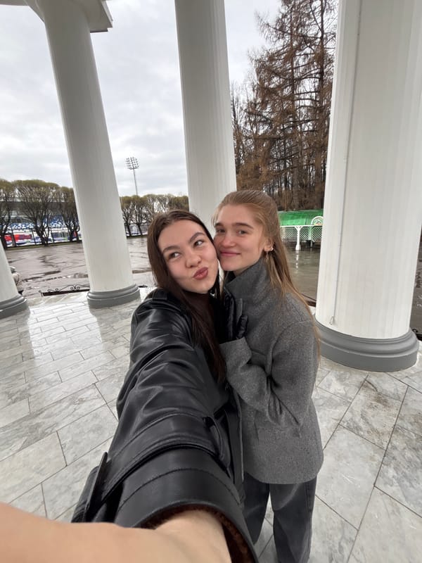 Women pose for photos at classical columns in Perm