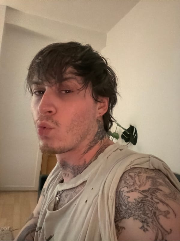 Tattooed selfie with silver cross pendant, London.