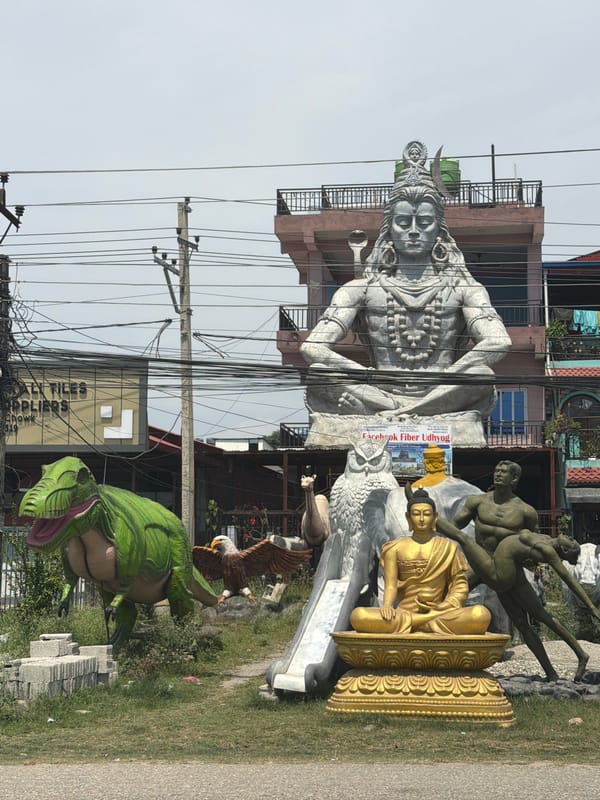Religious statues including seated Shiva deity displayed roadside in Nepal