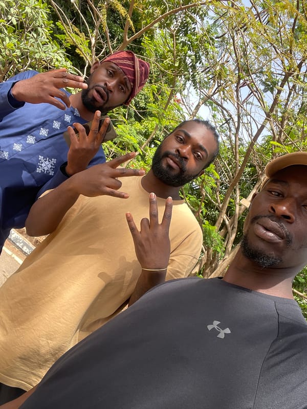 Three men gather outdoors in Jos, Nigeria