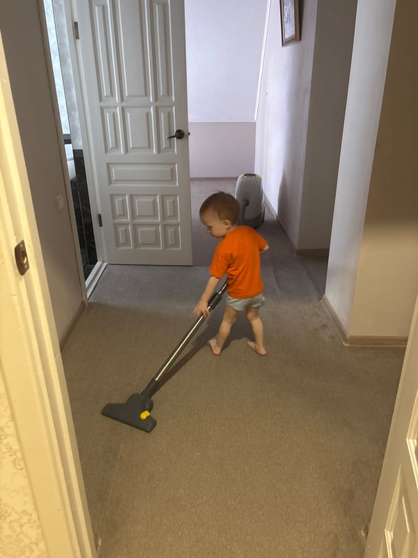 Toddler helps with household cleaning using vacuum cleaner