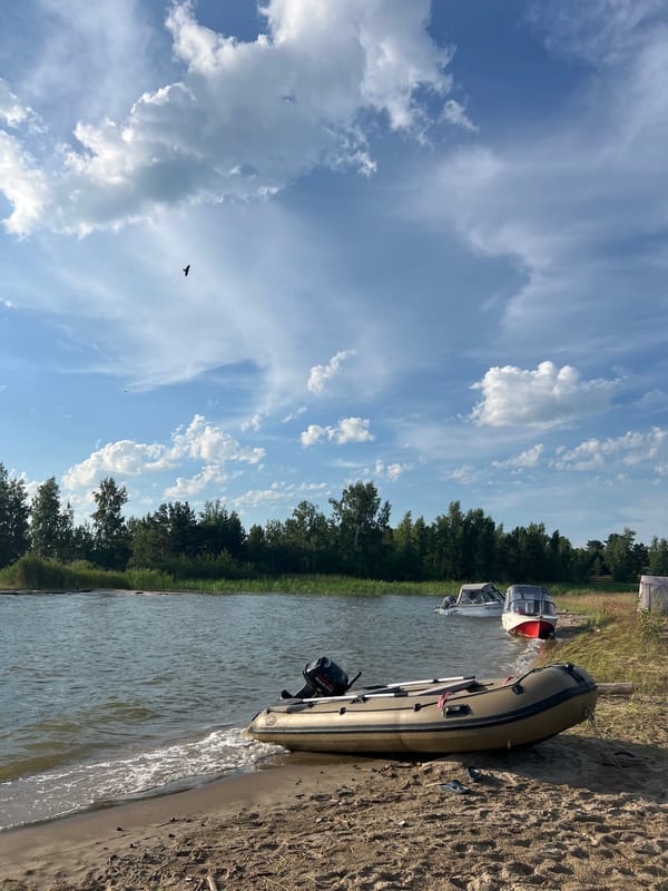 Boats on a calm Russian lakeshore under summer skies