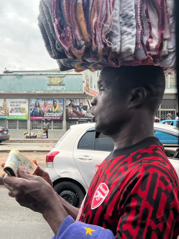 Street vendor counts money while balancing goods in Accra