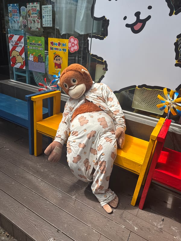 Pajama-clad stuffed monkey on a yellow bench in Jeju