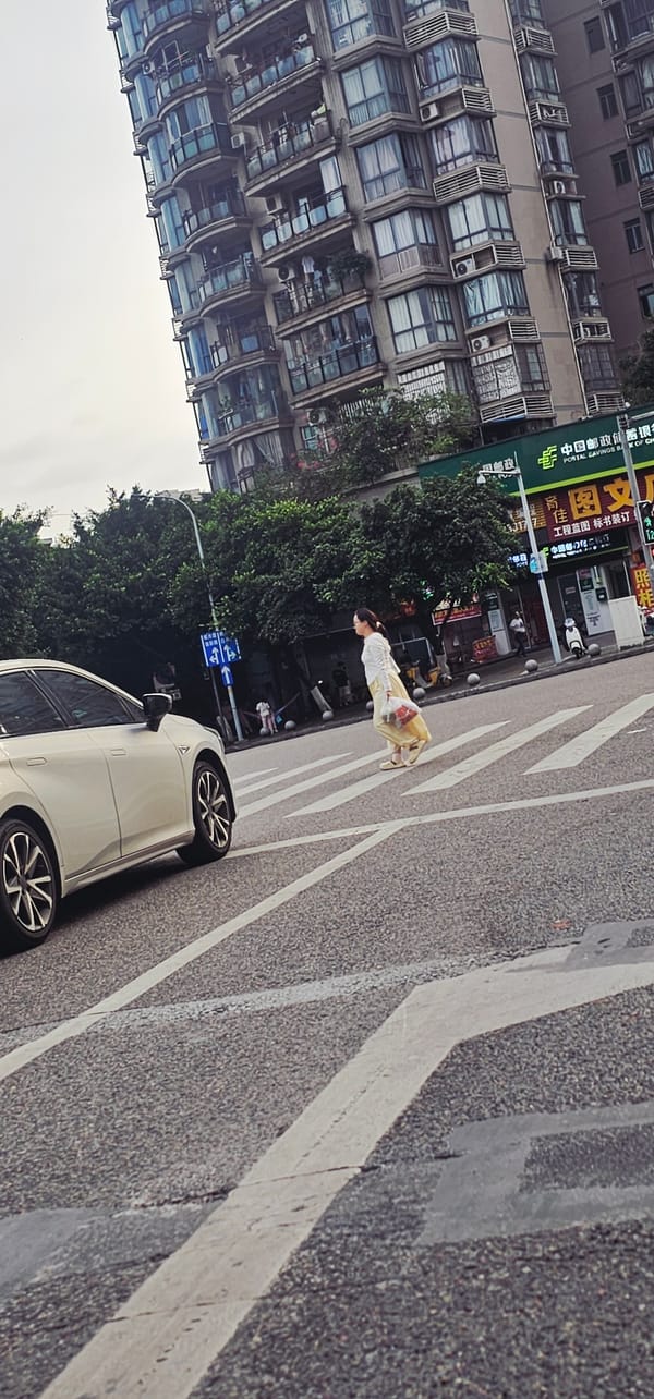 Woman crosses street while checking phone in Jiulongpo District