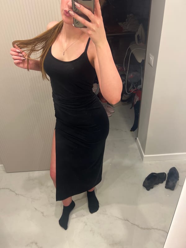 Mirror selfie in a black dress with a high slit.