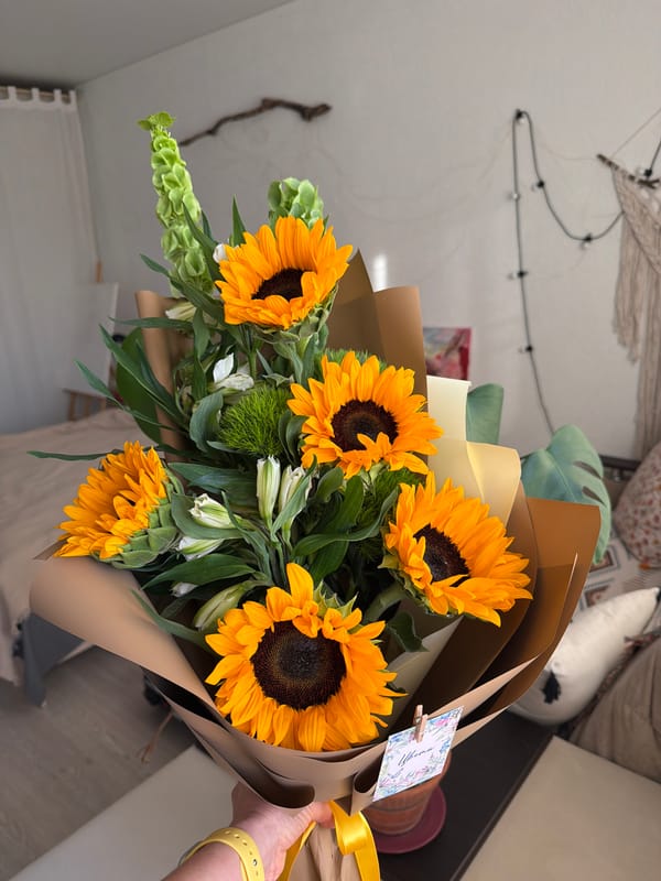 Person holds sunflower bouquet with yellow watch observed