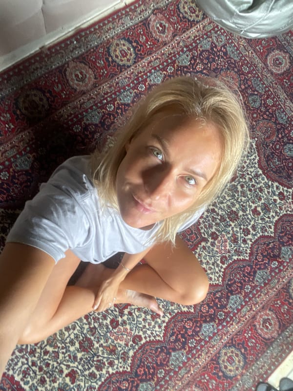 Woman poses on rug, near window in Baranovka