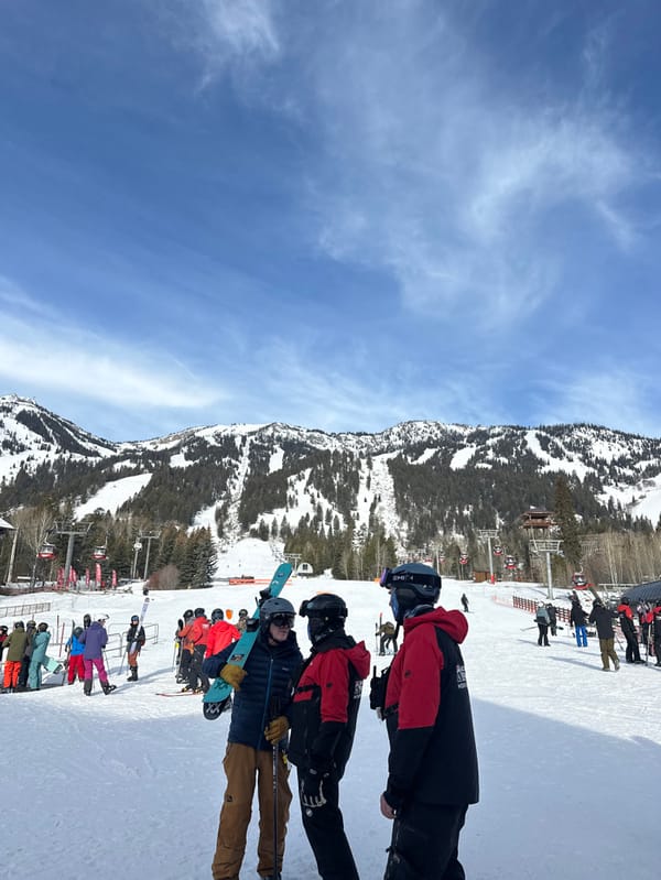 Skiers queue at Teton Village lift under blue skies