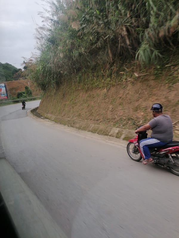 Two people spotted on curved hillside road in Vietnam
