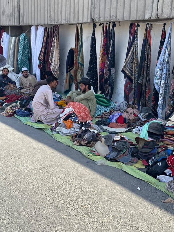 Clothing vendors rest among fabric piles at Quetta market