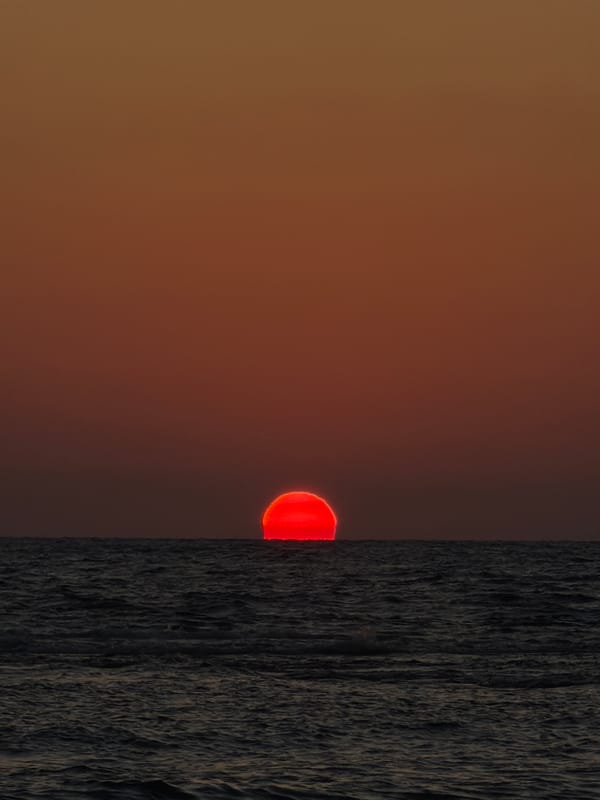 Red sun sets over the Mediterranean from a Tel Aviv beach