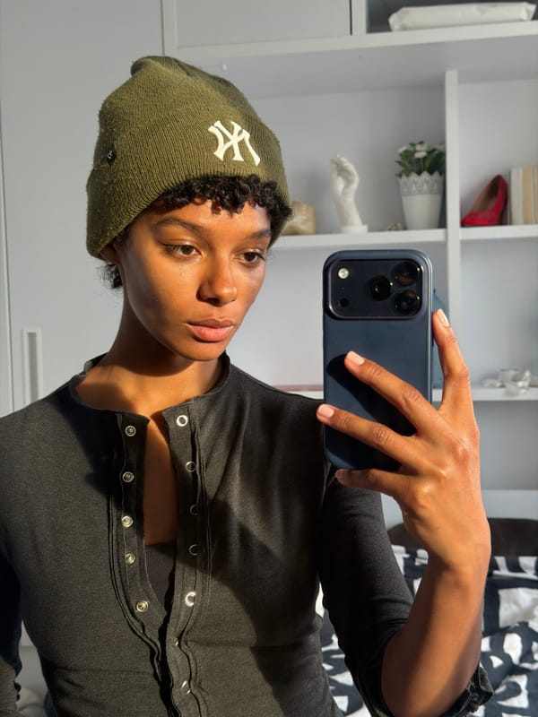 Person in NY beanie photographed multiple times indoors Paris