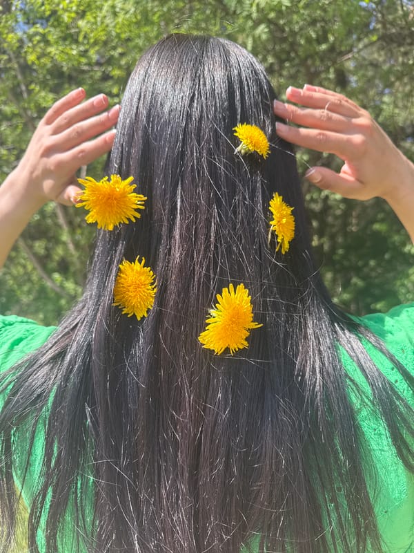 Person poses with dandelions in hair outdoors in Votkinsk