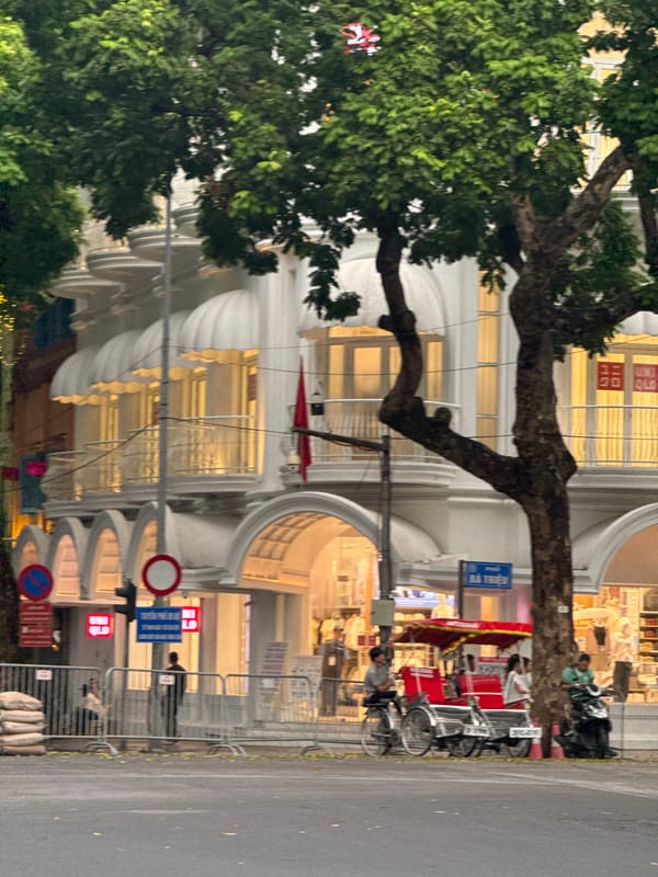Hanoi streetside: colonial facades, a parked scooter, cloudy morning