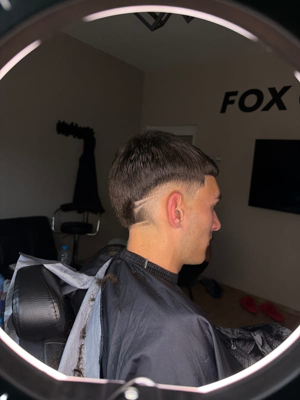 Man gets haircut at Septemvri barbershop under ring lights