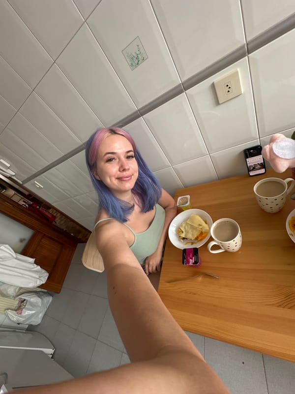 Woman takes colorful hair selfies at table in Gijón