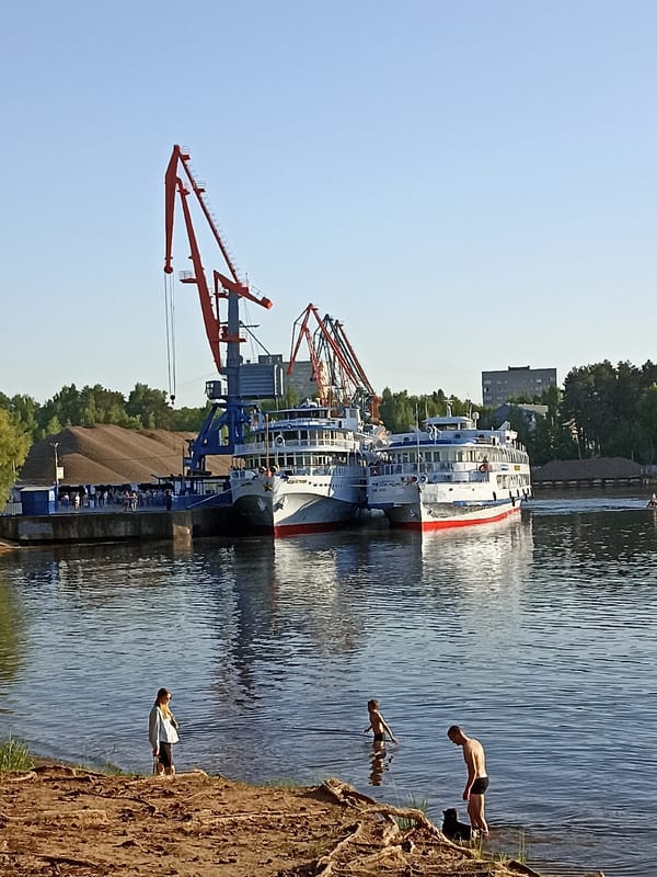 River cruise ships dock as passengers enjoy sunny waterfront afternoon
