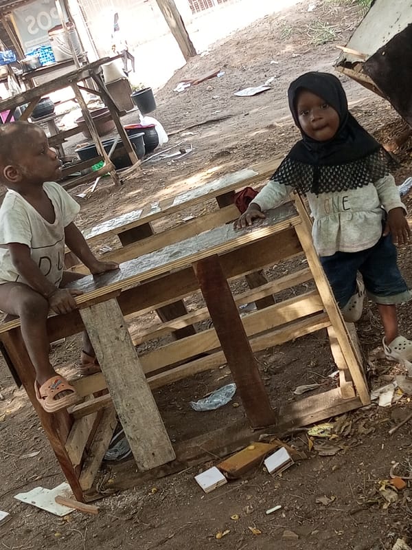 Two children playing outdoors near wooden structure