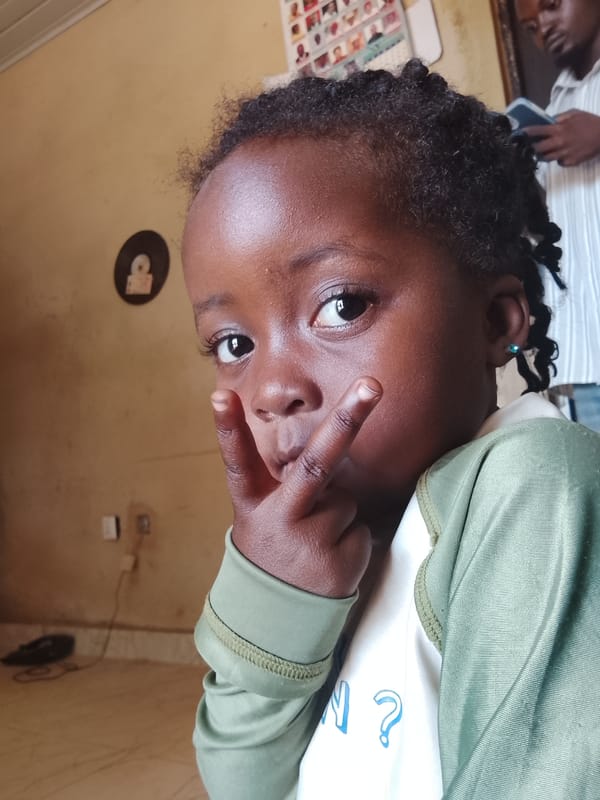 Child makes peace signs, smiles in Kuru Dungus