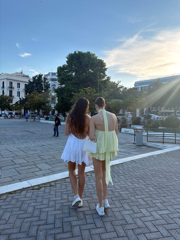 Two women in summer dresses stroll through historic Kavala