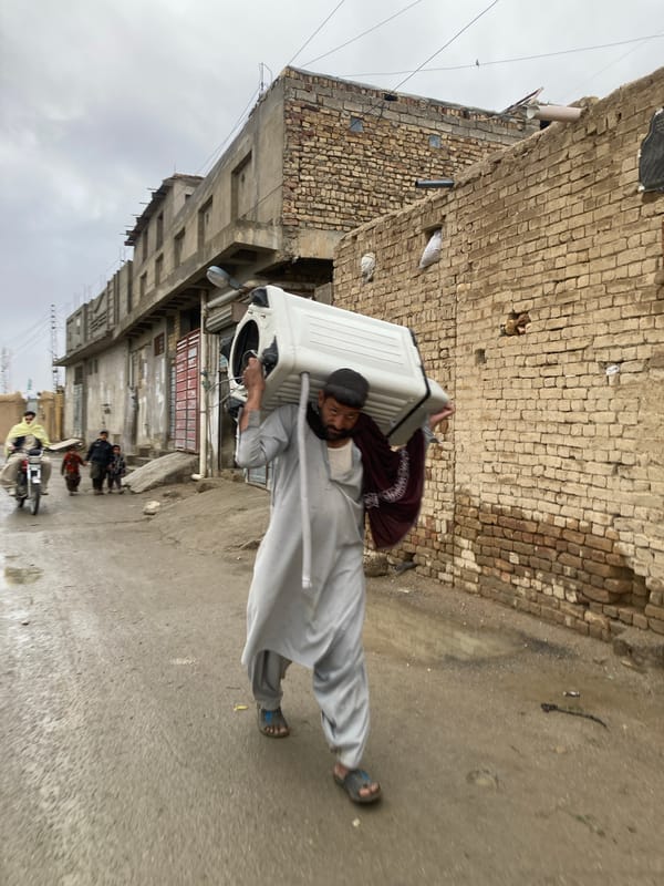 Men transport washing machine through narrow Quetta alley