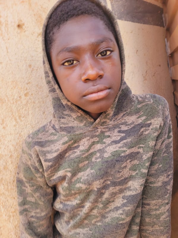 Young person resting in camouflage hoodie in Udu, Nigeria