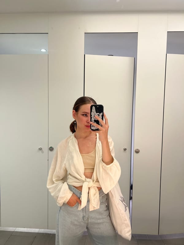 Woman in gold dress takes bathroom selfie while eating
