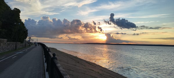 Cycling and strolling a waterfront promenade at sunset