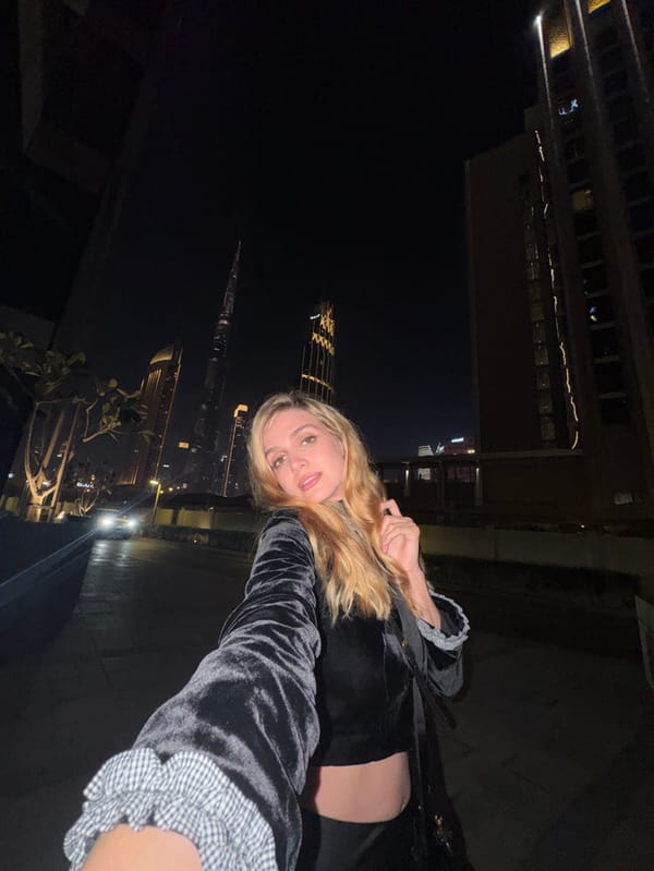 Woman photographs Dubai skyline selfies near Burj Khalifa at night