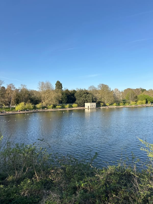 Pedestrians stroll lakeside pathway in Maidstone's Mote Park