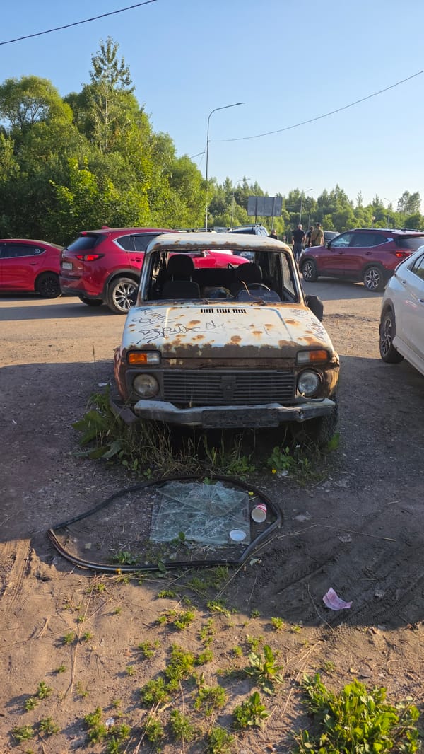 Rusted vehicles and ornate architecture at a lakeside setting
