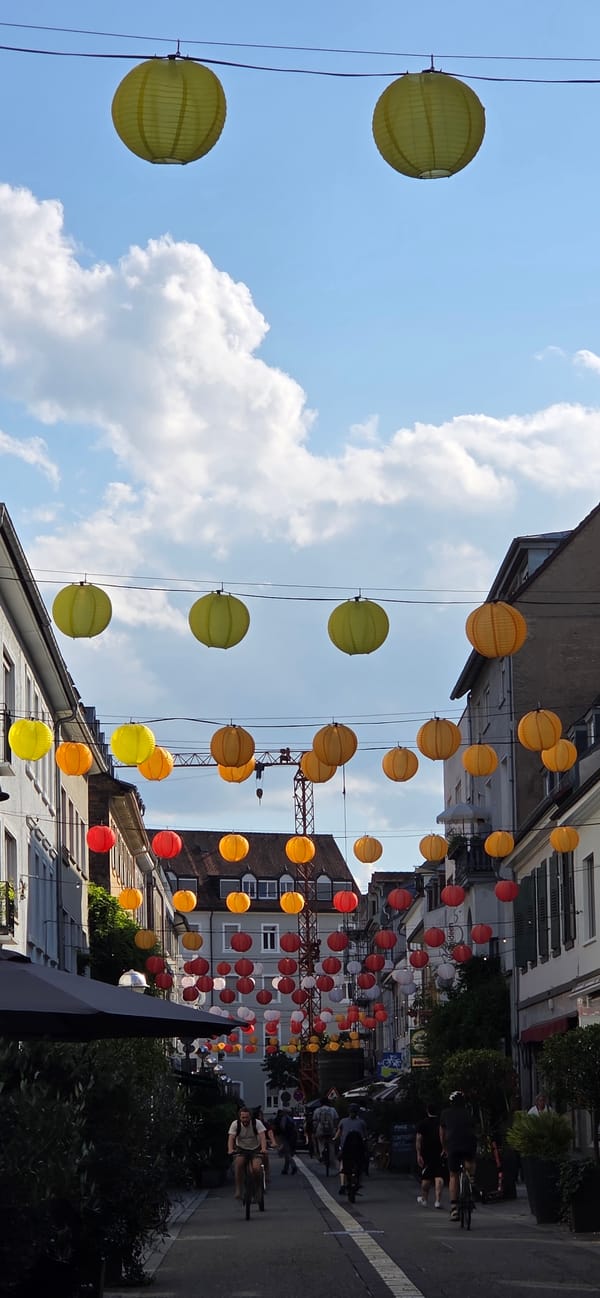 Lanterns and storefronts along a Karlsruhe street in summer