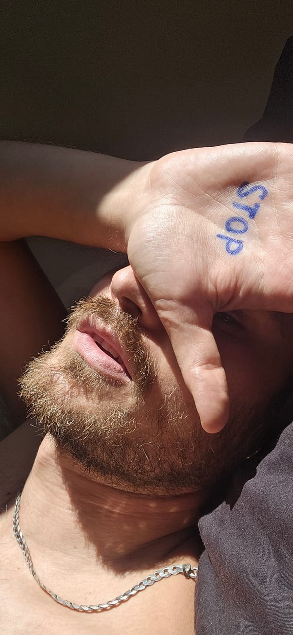 Hand with 'stop' written in marker, held over one eye