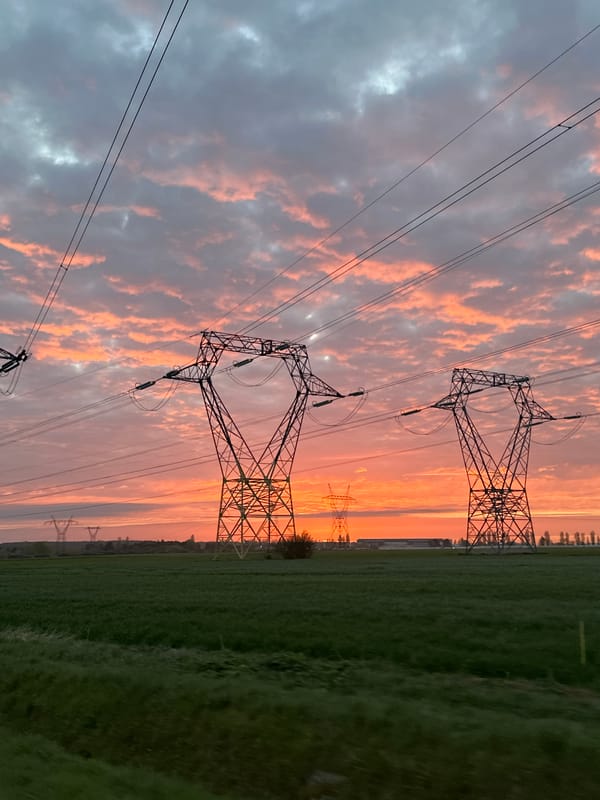Dramatic sunrise illuminates rural French landscape with power towers
